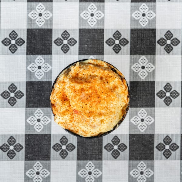 Overhead view of a creamy dish with orange seasoning, on a black and white checkered tablecloth.