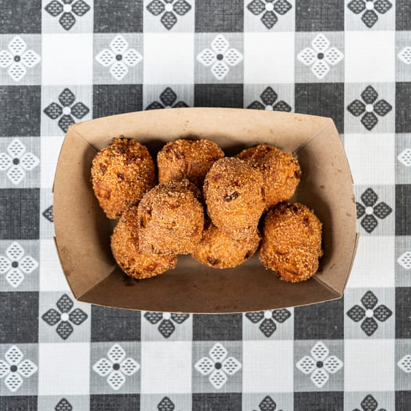Hush puppies in a brown paper tray on a black and white checkered tablecloth.